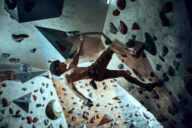 libero scalatore giovane arrampicata masso artificiale al chiuso - hanging on rock rock climbing foto e immagini stock