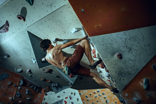 libero scalatore giovane arrampicata masso artificiale al chiuso - hanging on rock rock climbing foto e immagini stock