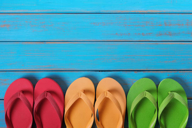 istock Flip flops in a row old weathered blue beach wood background 986492014