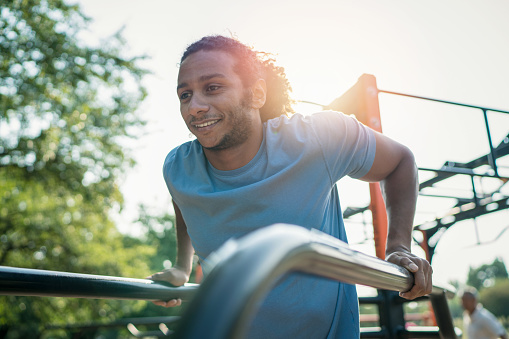 Attractive African-American male training at the fitness racks in the park