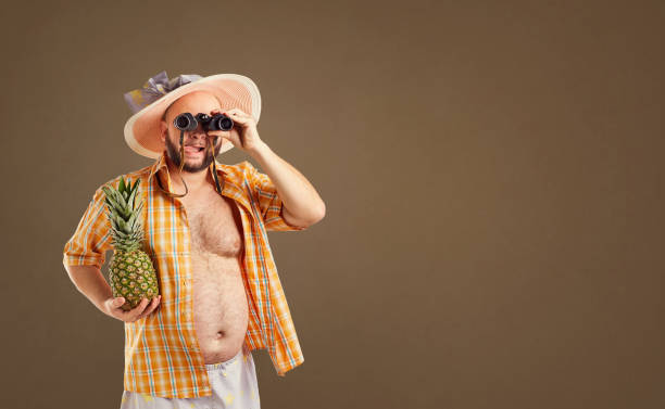 istock Thick funny man with a beard in a hat with binoculars 986496862
