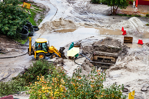 Repair of heating, bulldozer digging the ground in the rain