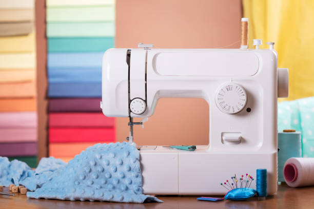 istock Sewing machine and cloth in work, sewing supplies on table 986508652