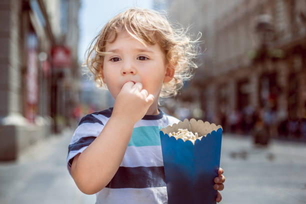 Little boy eating popcorn in the city