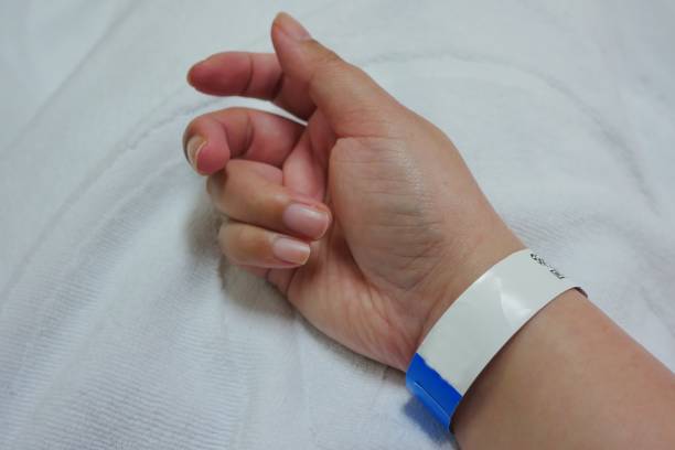 una mano di paziente asiatica adulta con braccialetto ospedaliero. - braccialetto di identificazione foto e immagini stock