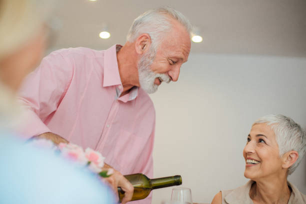 istock Happy woman looking at senior man with wine bottle 986513498