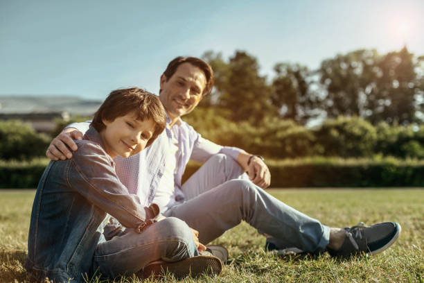 istock Dad and son sitting on the grass smiling and hugging 986515312