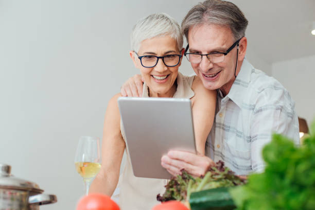istock Mature couple hugging and looking at digital tablet in the kitchen 986518462