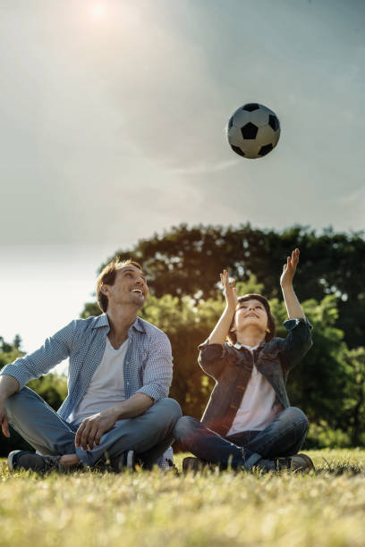 istock Smiling son and dad sitting on the grass 986520226