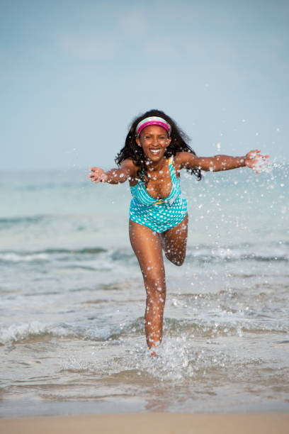 istock Woman splashing water at the beach. 986522230
