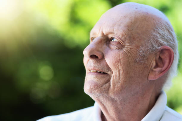 istock Senior man smiling in the sunshine looks contented 986523622