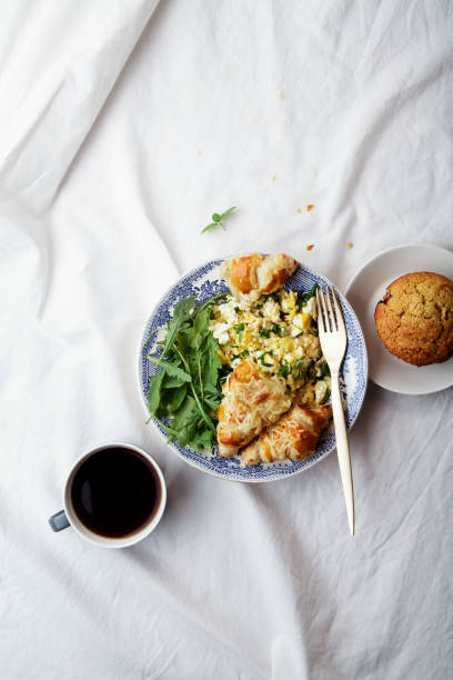 istock Breakfast in bed. Scrambled eggs with cheese croissants, raspberry muffin and black coffee. Morning treat concept. Composition with copy space. 986540616
