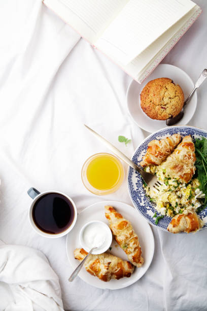 istock Breakfast in bed. Scrambled eggs with cheese croissants, raspberry muffin and black coffee. Morning treat concept. Vertical composition with copy space. 986540670
