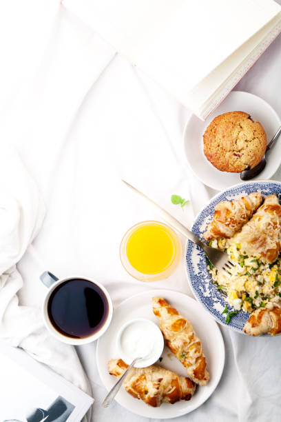 istock Breakfast in bed. Scrambled eggs with cheese croissants, raspberry muffin and black coffee. Morning treat concept. Vertical composition with copy space. 986540686