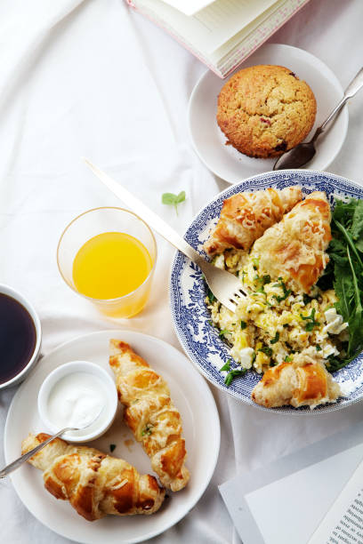 istock Breakfast in bed. Scrambled eggs with cheese croissants, raspberry muffin and black coffee. Morning treat concept. Composition with copy space. 986540756