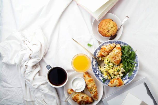 istock Breakfast in bed. Scrambled eggs with cheese croissants, raspberry muffin and black coffee. Lazy morning concept. Flat lay with copy space. 986540772