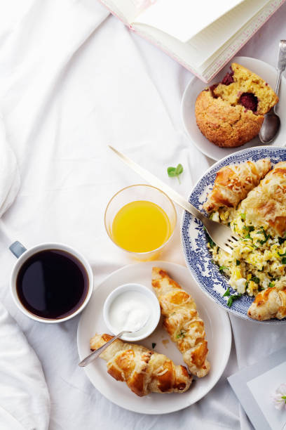 istock Breakfast in bed. Scrambled eggs with cheese croissants, raspberry muffin and black coffee. Morning treat concept. Composition with copy space. 986540860