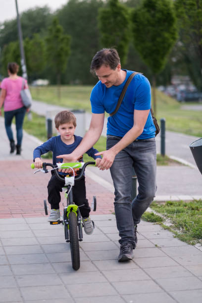 istock Little boy learning to ride a bicycle with help of his father. 986557054