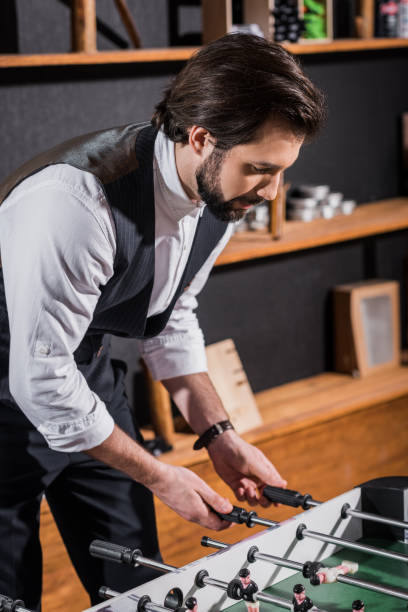 istock handsome bearded man in vest playing table football 986565592