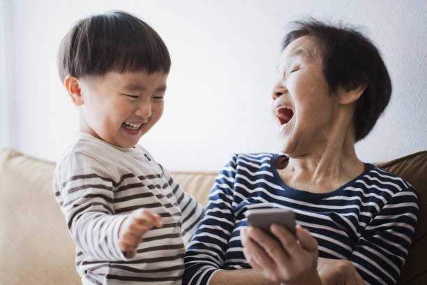 祖母と家で一緒にスマート フォンを使用して少年 - family grandmother child happiness ストックフォトと画像