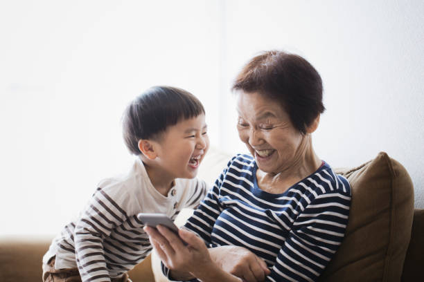 할머니와 함께 집에서 스마트 휴대 전화를 사용 하는 소년 - asia old japan family 뉴스 사진 이미지