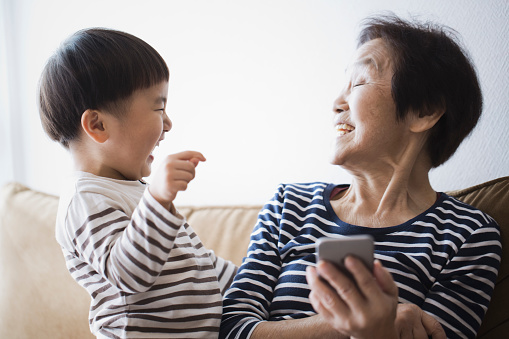 An asian senior woman and her grand son using a smartphone together.