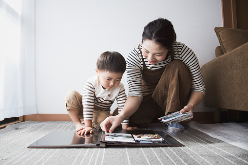 An asian mother and boy making a photo album at home.