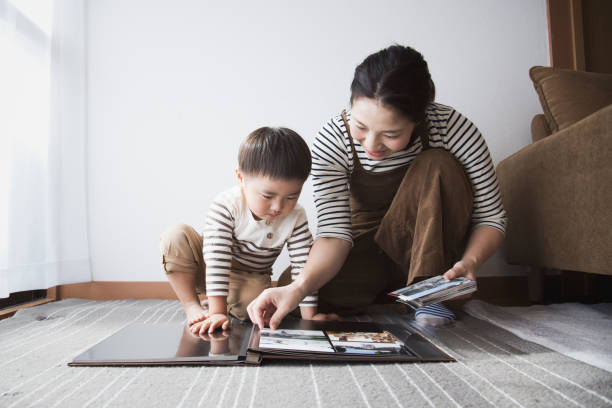 Mother and son making a photo album together An asian mother and boy making a photo album at home. family photos album stock pictures, royalty-free photos & images