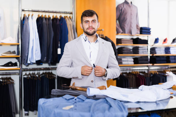 istock Smiling young male customer choosing new jacket 986567328