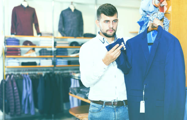 istock man choosing casual jacket in fashion store 986567400