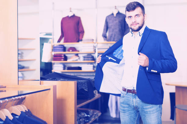 istock man choosing casual jacket in fashion store 986567424