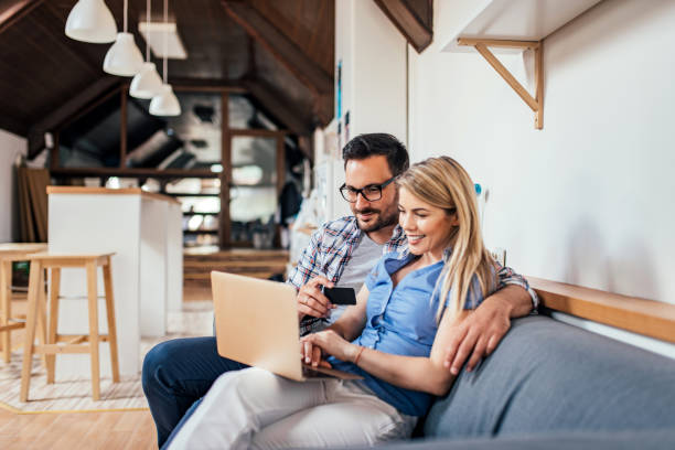 istock Couple shopping online while sitting on the sofa in modern apartment. 986568398