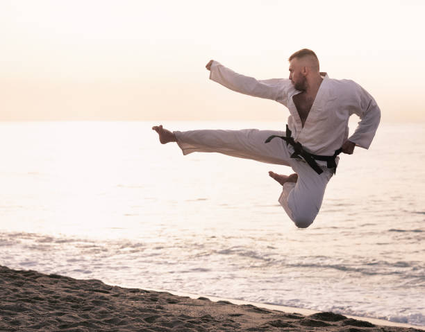 istock Guy doing karate poses at  sunset sea shore 986572168