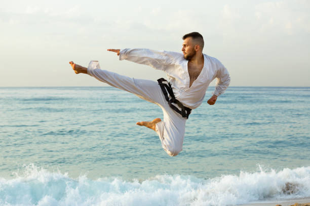 istock Guy doing karate poses at  sunset sea shore 986572184