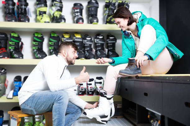 istock Guy helping smiling girlfriend to trying on ski boots in store 986572762