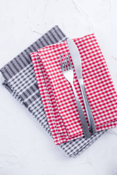 istock Table towels of red and gray color, fork and knife. White table. Servlet for lunch. Copy space 986573268