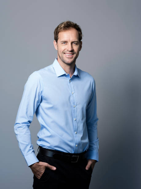 istock Smiling businessman standing with hands in pockets 986574046