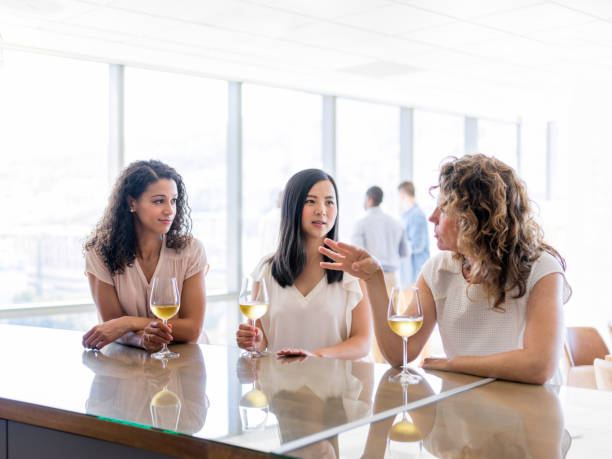 istock Businesswomen with wineglasses discussing at table 986580432