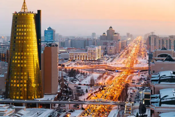 A view from above on a large avenue that goes down to the horizon, and a golden skyscraper of minestry in Astana, Kazakhstan.