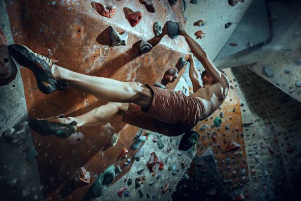libero scalatore giovane arrampicata masso artificiale al chiuso - hanging on rock rock climbing foto e immagini stock