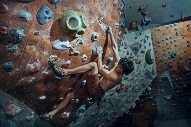 libero scalatore giovane arrampicata masso artificiale al chiuso - climbing rock men mountain climbing foto e immagini stock