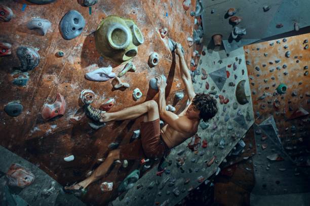 istock Free climber young man climbing artificial boulder indoors 986592702