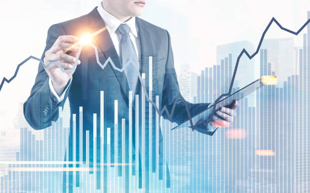 istock Businessman with glowing pen, drawing city graphs 986596014