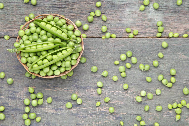 istock Fresh green peas in basket on wooden table 986596576