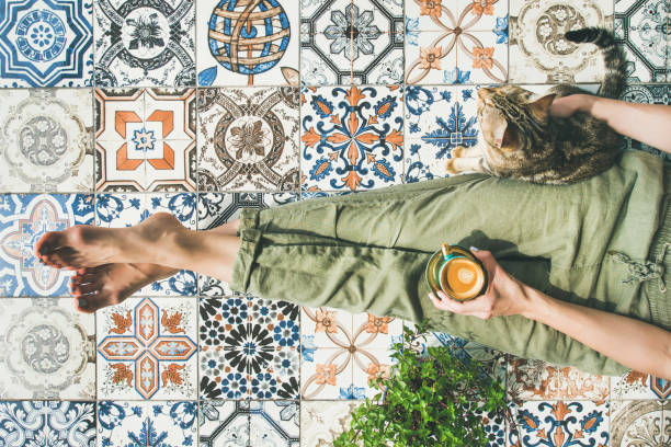 Woman, coffe and cat Lazy morning on terrace. Flat-lay of womans legs in cosy linen pants, plant, cat and cup of coffee in hand over colorful moroccan tile floor, top view moroccan woman stock pictures, royalty-free photos & images