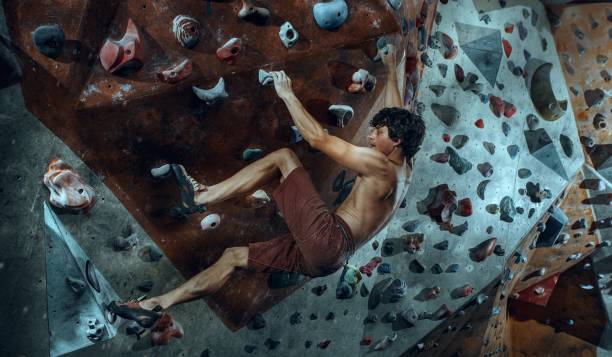 libero scalatore giovane arrampicata masso artificiale al chiuso - hanging on rock rock climbing foto e immagini stock