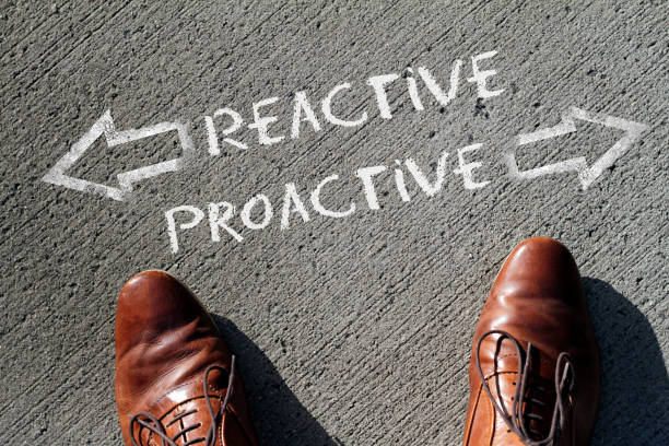 Finding the right business strategy: reactive or proactive? A man stands in front of the words "reactive" and "proactive" written with chalk onto the floor. initiative stock pictures, royalty-free photos & images