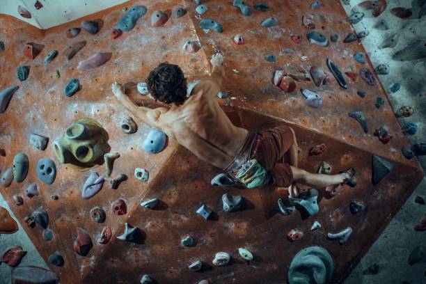 libero scalatore giovane arrampicata masso artificiale al chiuso - hanging on rock rock climbing foto e immagini stock