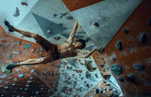 libero scalatore giovane arrampicata masso artificiale al chiuso - hanging on rock rock climbing foto e immagini stock