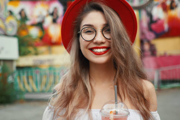 istock Cheerful young woman holding a drink while smiling 986621852